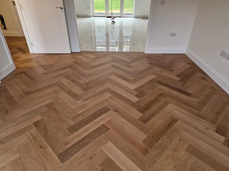 Warm-toned herringbone floor in a living room leading to garden doors