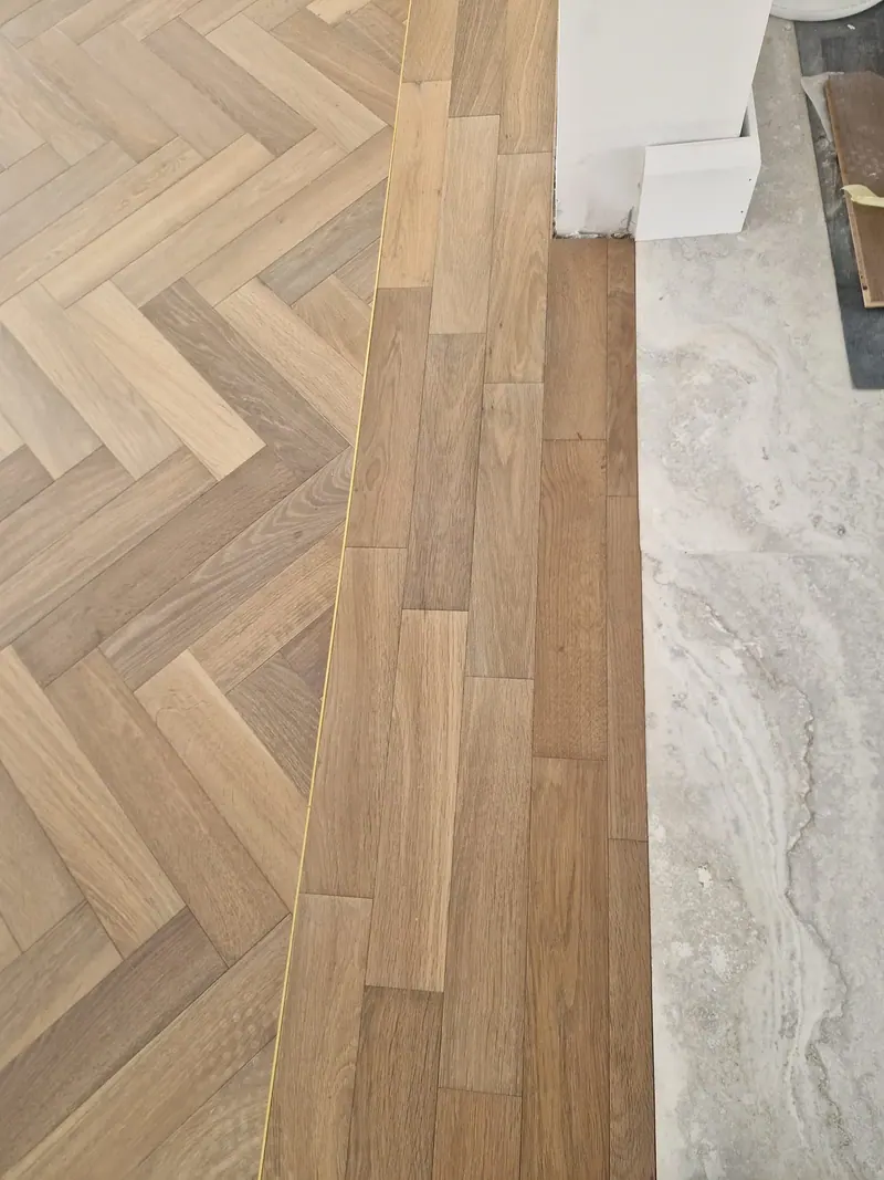 Herringbone floor meeting stone tile at a threshold