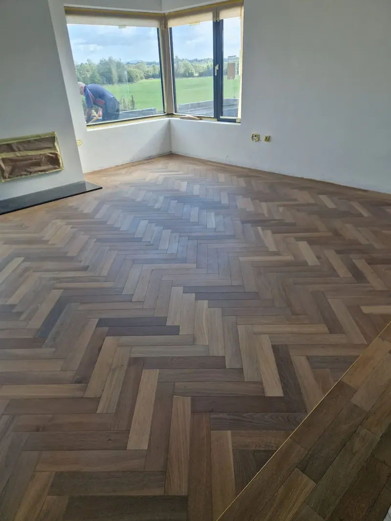 Dark herringbone floor in a living room with a bay window