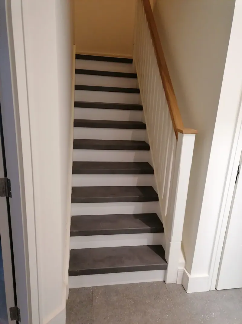 Staircase with dark treads, white risers and an oak handrail